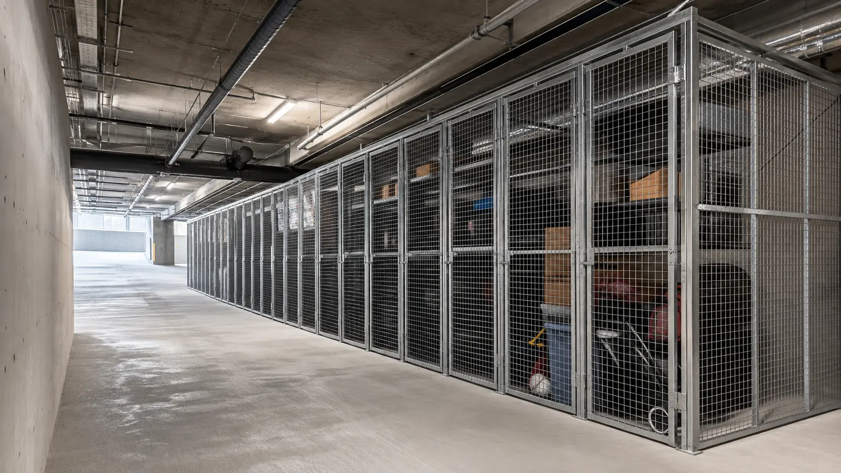 Row of galvanized mesh tenant storage cages in a concrete parkade
