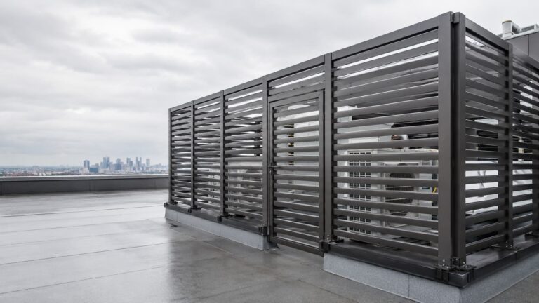 Louvered steel screen enclosing rooftop mechanical equipment above a city skyline