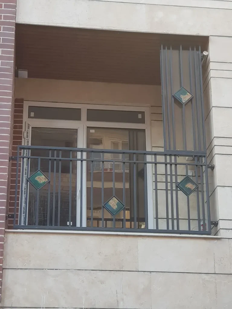 Steel balcony guardrail with vertical bars and diamond ceramic tile inserts framed in steel