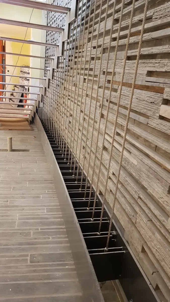 Long run of vertical cables along a mezzanine edge with the anchor channel below