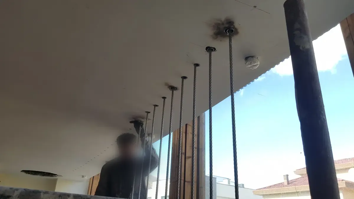 A wire rope being tensioned into its anchor point in the soffit above