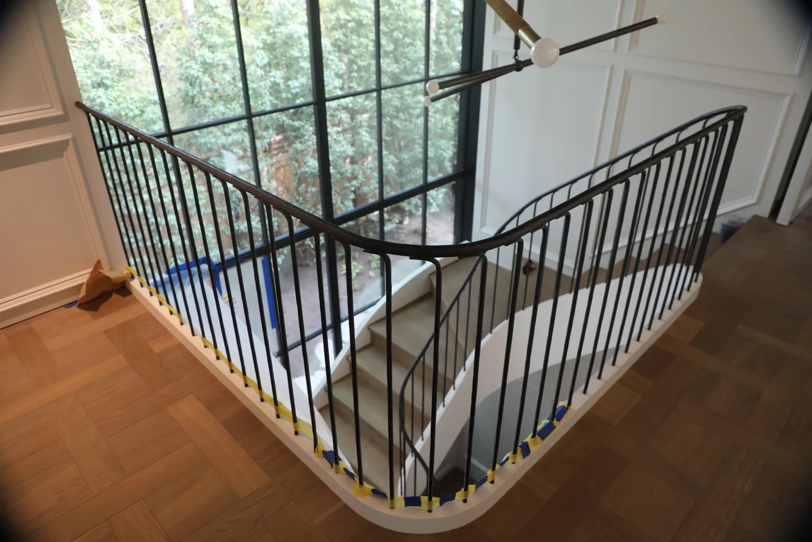 Curved interior steel guardrail with round vertical bars and a shaped continuous handrail wrapping a stair opening