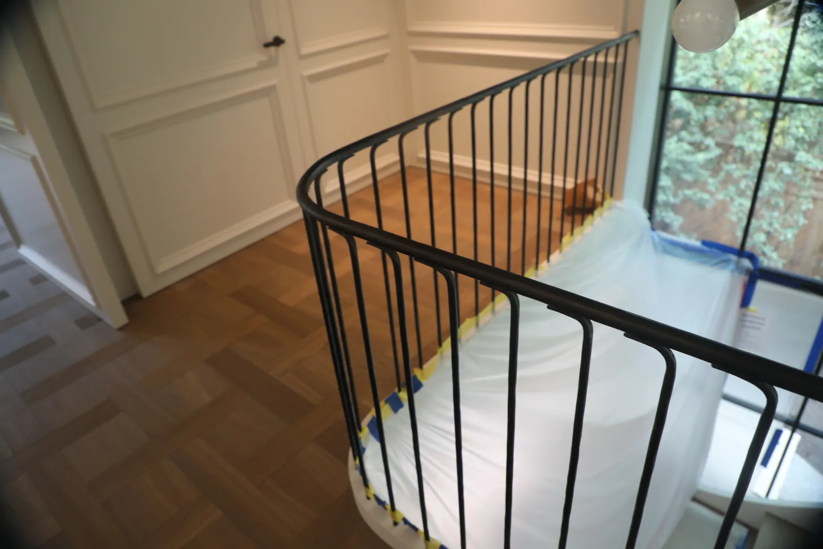 Interior steel guardrail curving around a landing, with a shaped handrail running continuously through the radius