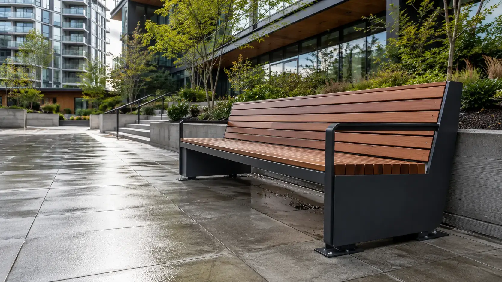 Steel and timber slat bench on a wet plaza in front of a landscaped residential building