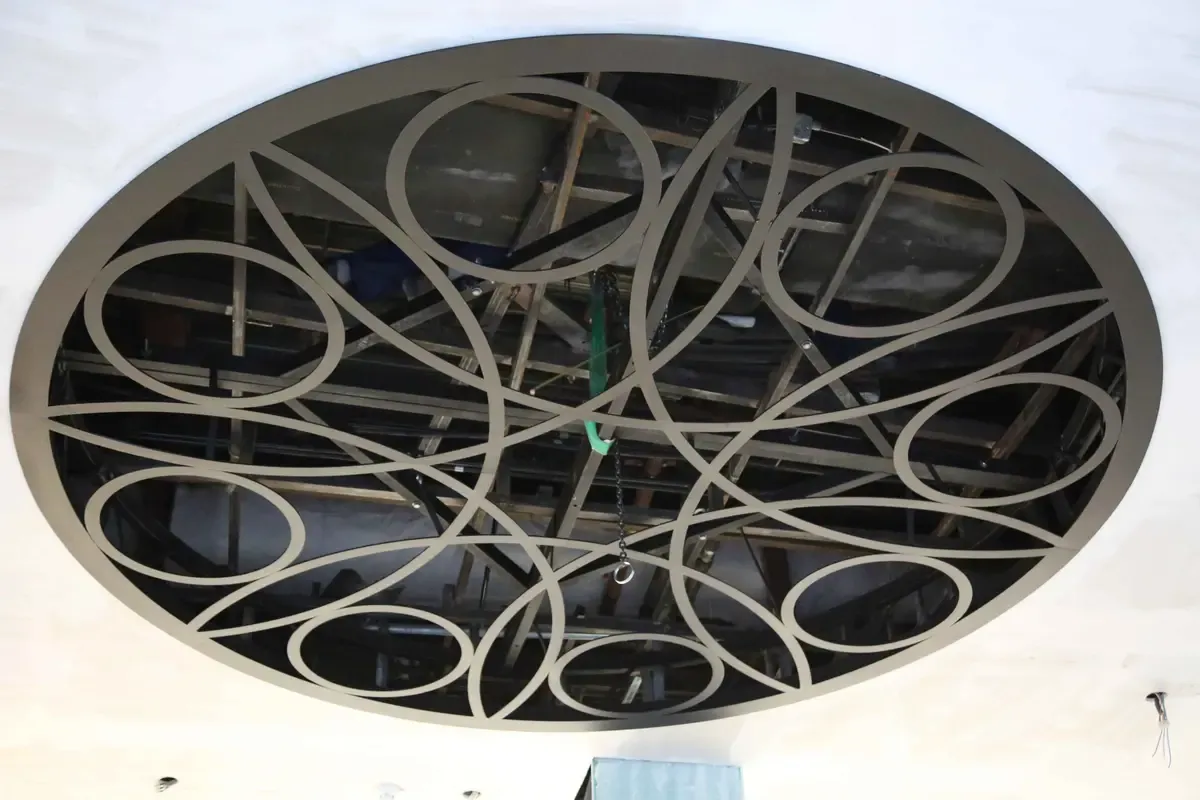 Large circular steel ceiling feature with an interlocking cut circle pattern, seen from below