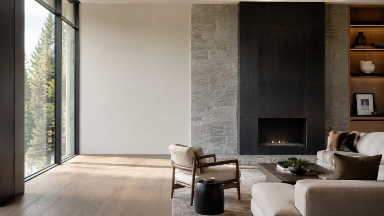 Floor-to-ceiling blackened steel fireplace surround beside a stone chimney breast in a modern living room with a lit gas fire