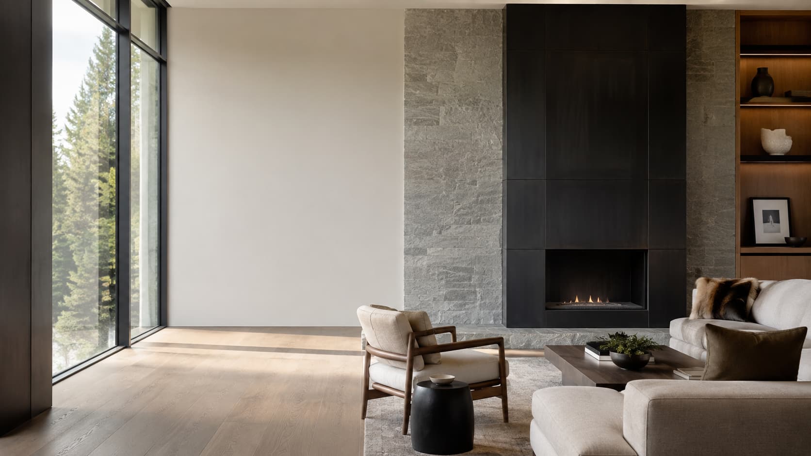 Floor-to-ceiling blackened steel fireplace surround beside a stone chimney breast in a modern living room with a lit gas fire