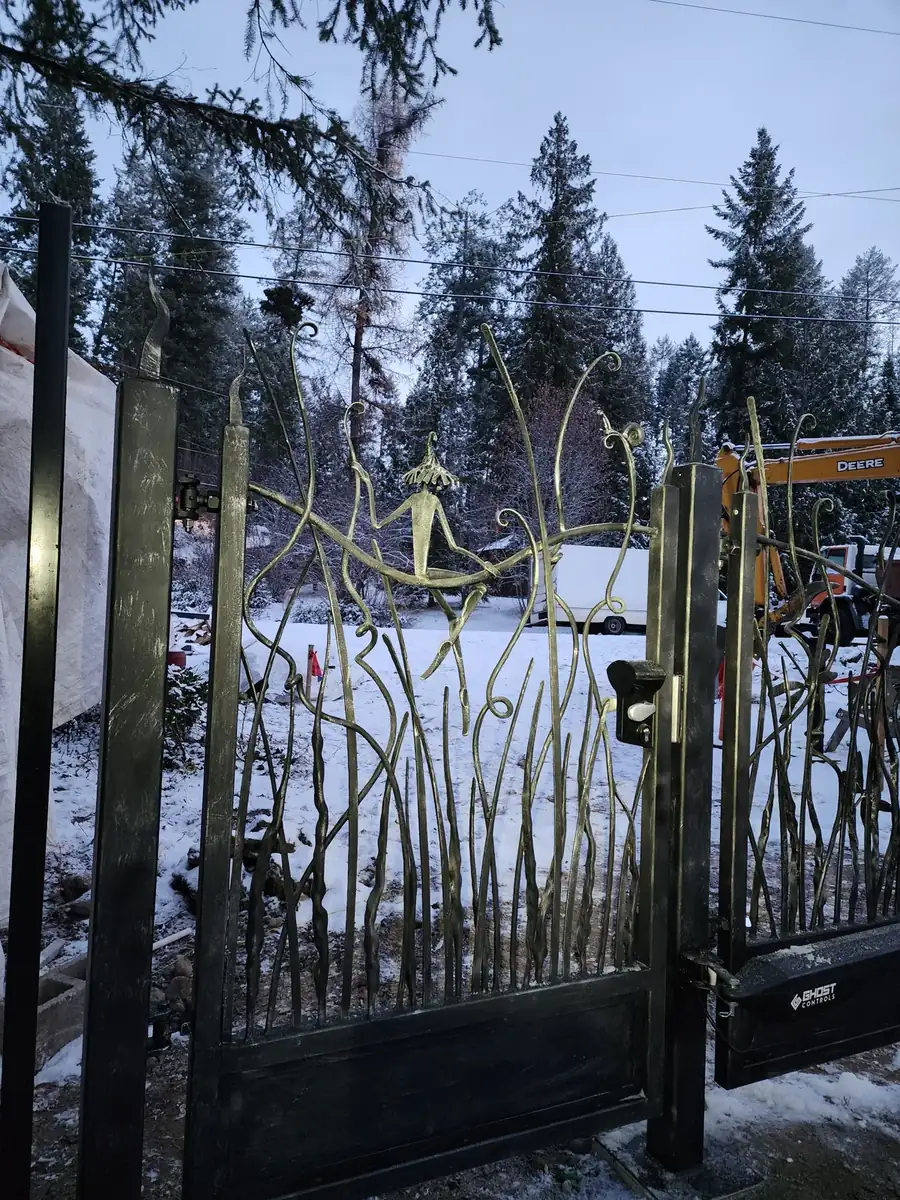Forged gate leaf showing branch and tendril bars with gilded highlights along the raised surfaces