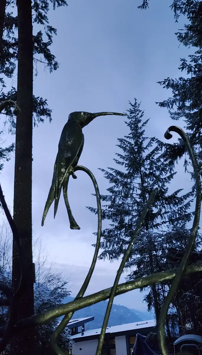 Hand-forged hummingbird with a long beak mounted on a forged vine bar