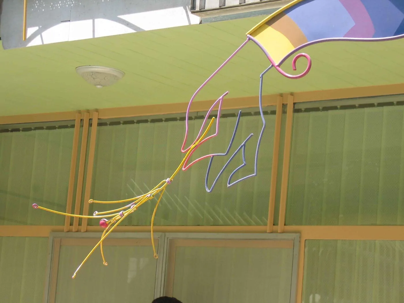 A figure drawn in bent steel rod, mounted clear of the wall as an open outline