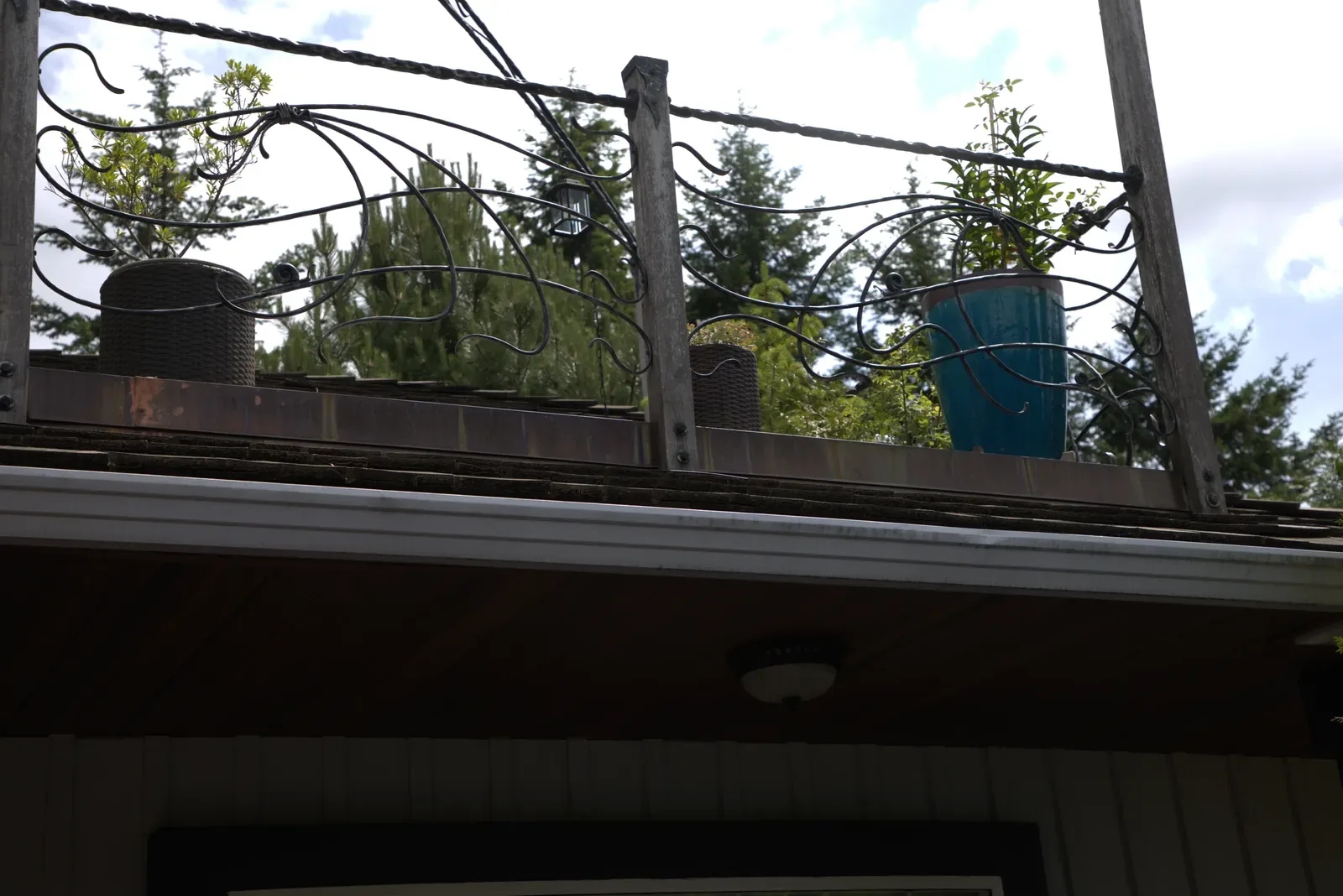 Forged scrollwork infill panels along a deck railing, seen against the sky