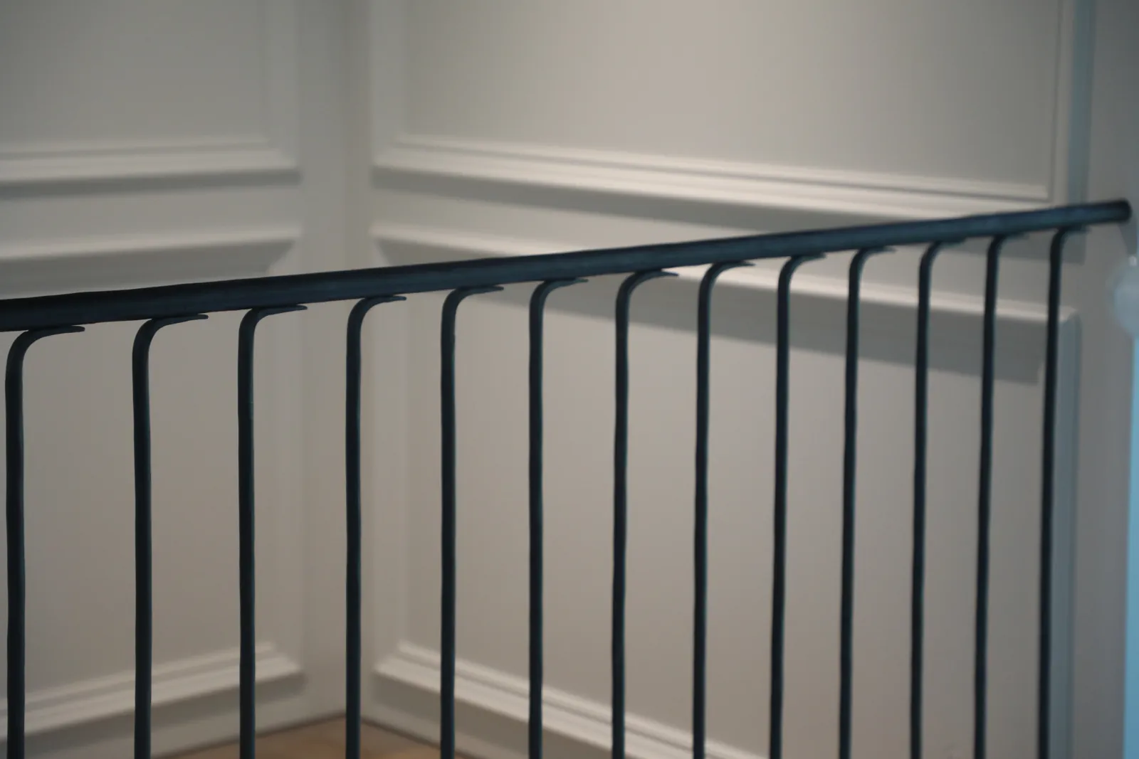 Close view of a shaped steel handrail profile above evenly spaced round balusters