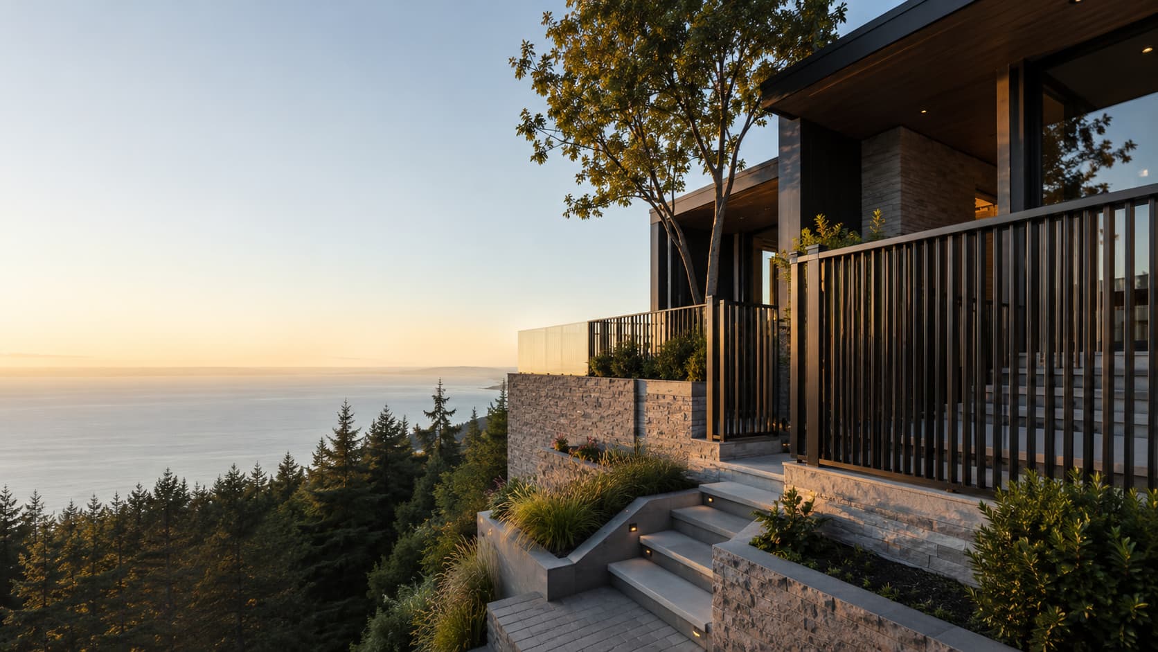 Black steel picket railing and stair guard on a terraced West Vancouver property overlooking Howe Sound at sunset