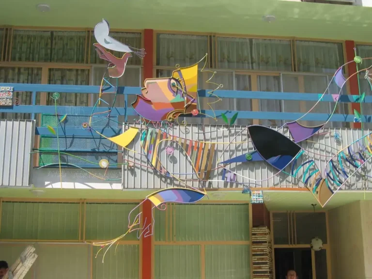 Sculptural painted steel bird and fish figures mounted along a blue steel balcony frame