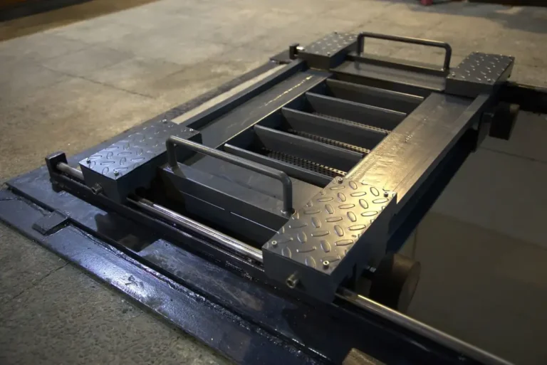 Welded steel jack trolley with checker plate end platforms, tubular handles and a perforated deck, finished in grey
