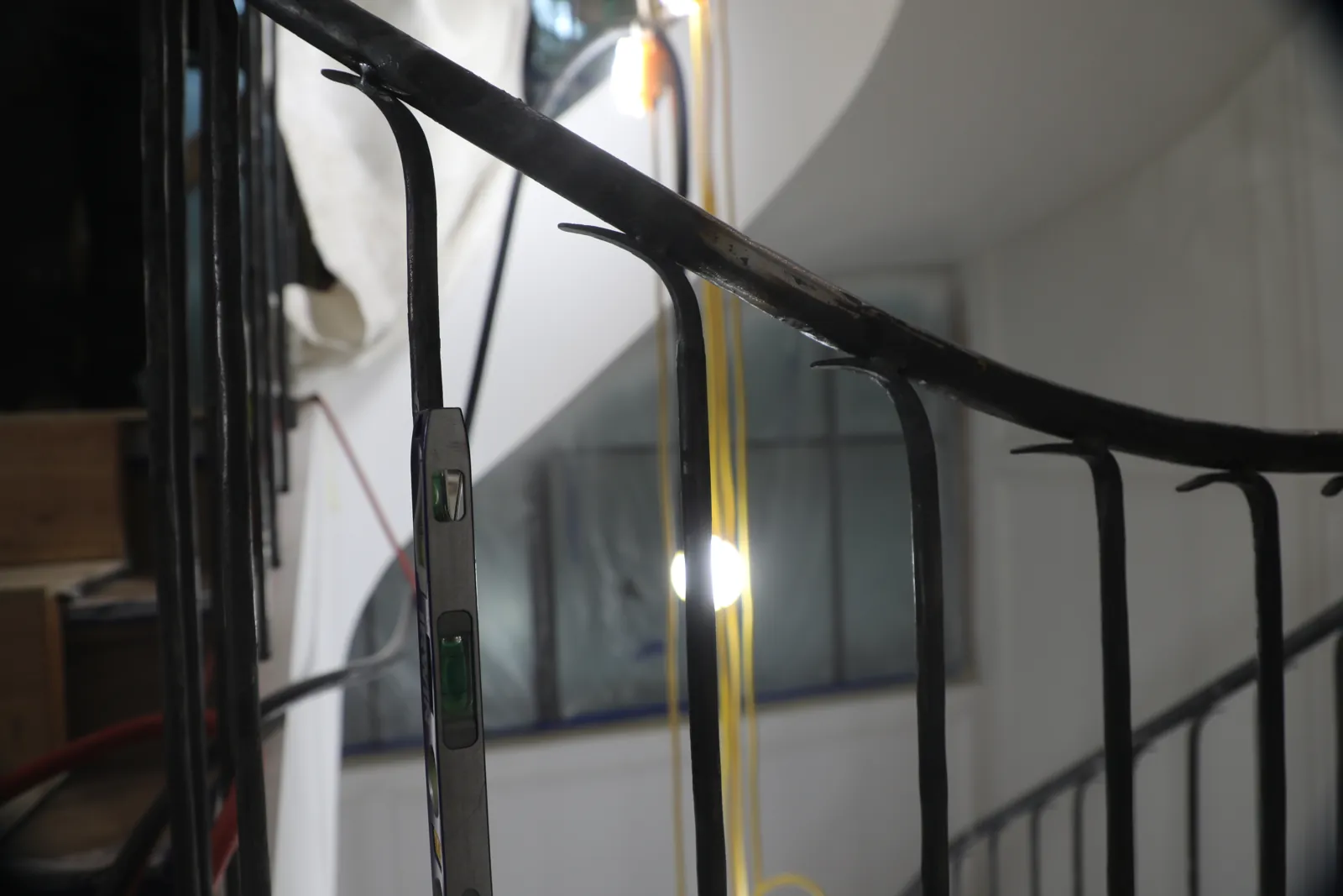 Shaped steel handrail with a scrolled return, being checked for level during installation
