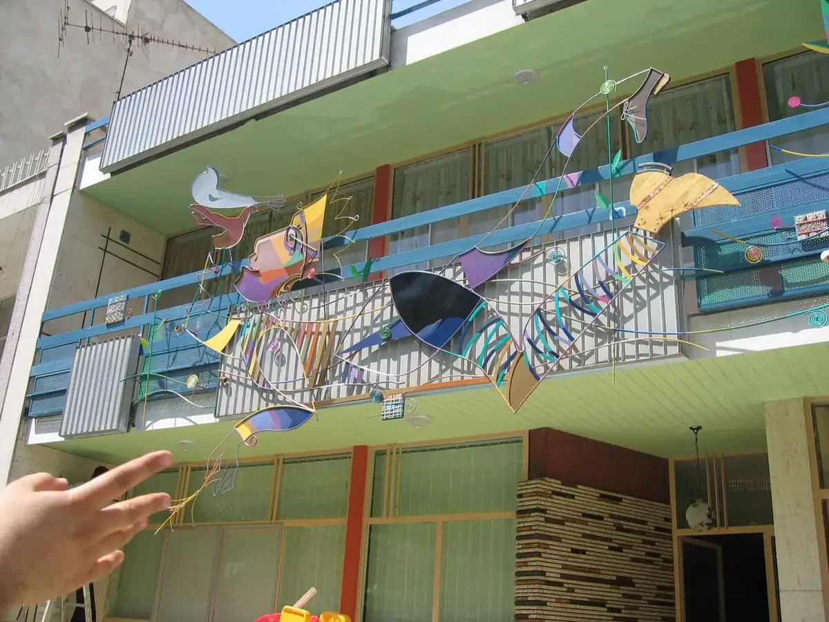 Wide view of a painted steel art installation running across a building elevation