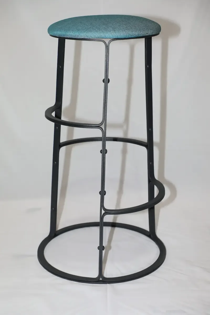Tall black steel bar stool with a round upholstered seat and a hooped foot ring