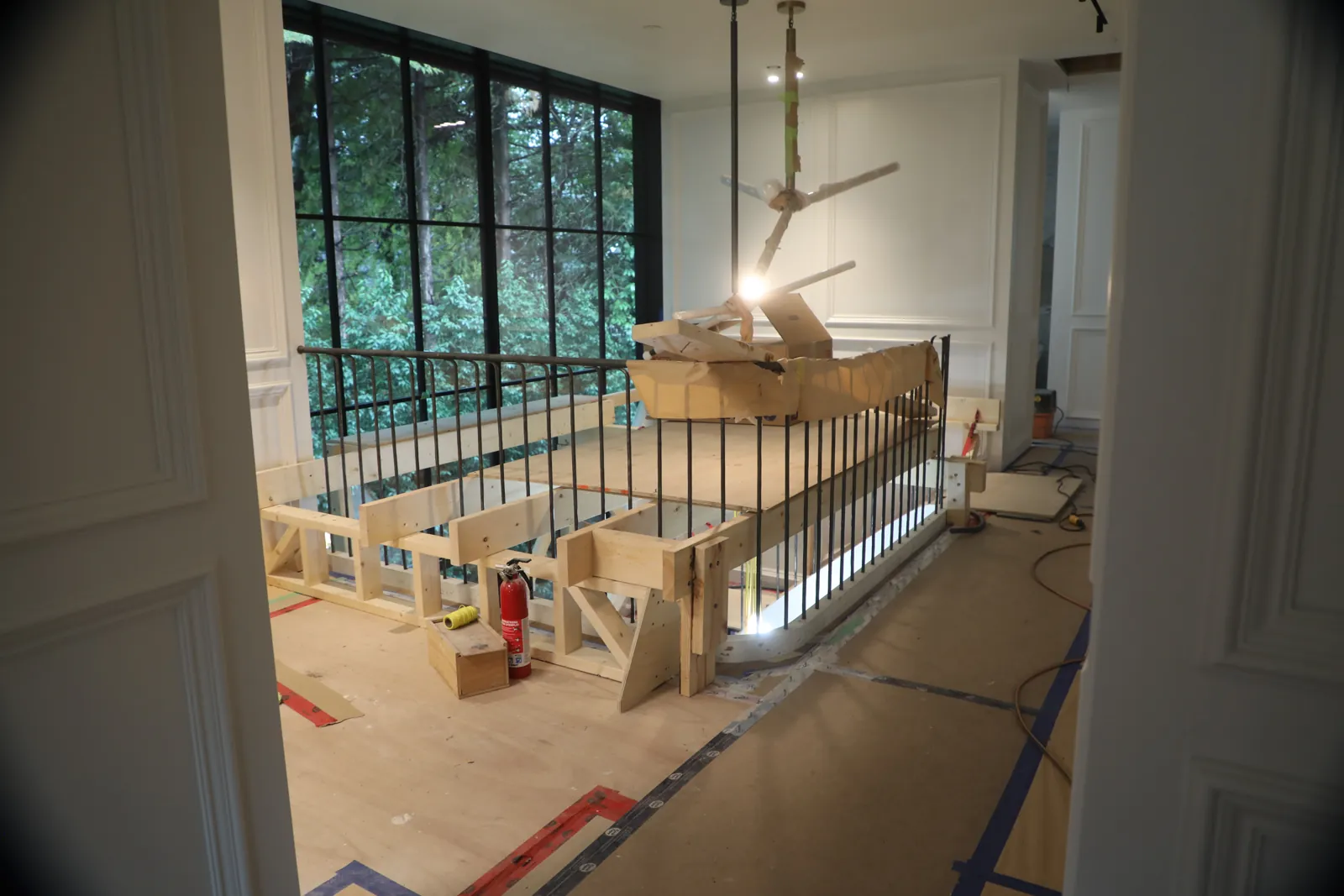 Steel guardrail sections braced in position during installation in an unfinished interior
