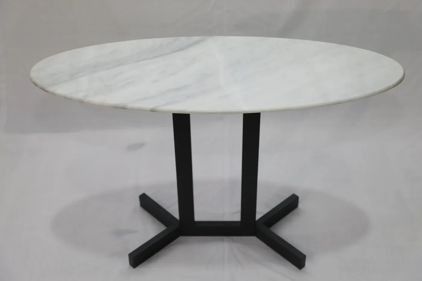 Custom round dining table with a white marble top on a matte black steel pedestal base