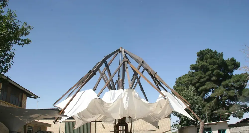 Steel folding arm mechanism part way through opening, with the fabric canopy still gathered