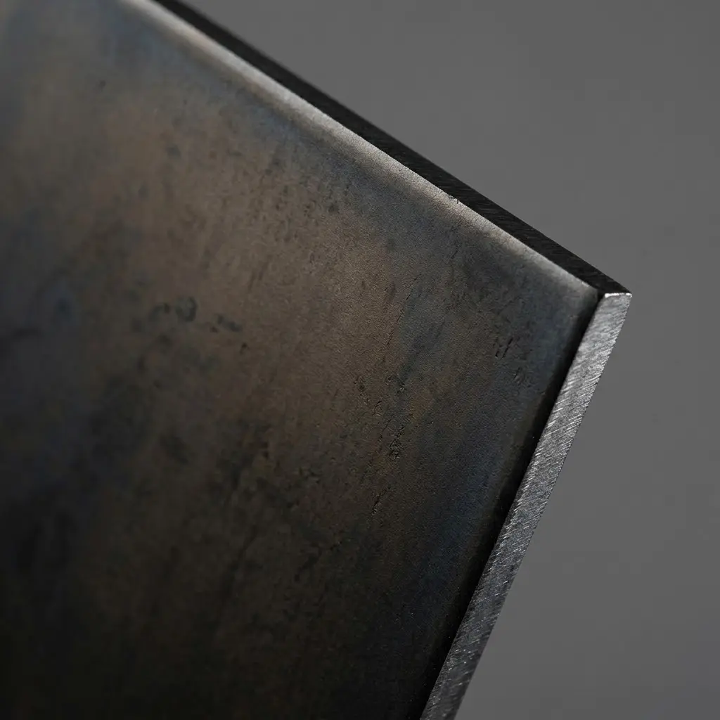 Blackened steel finish sample with a visible cut metal edge