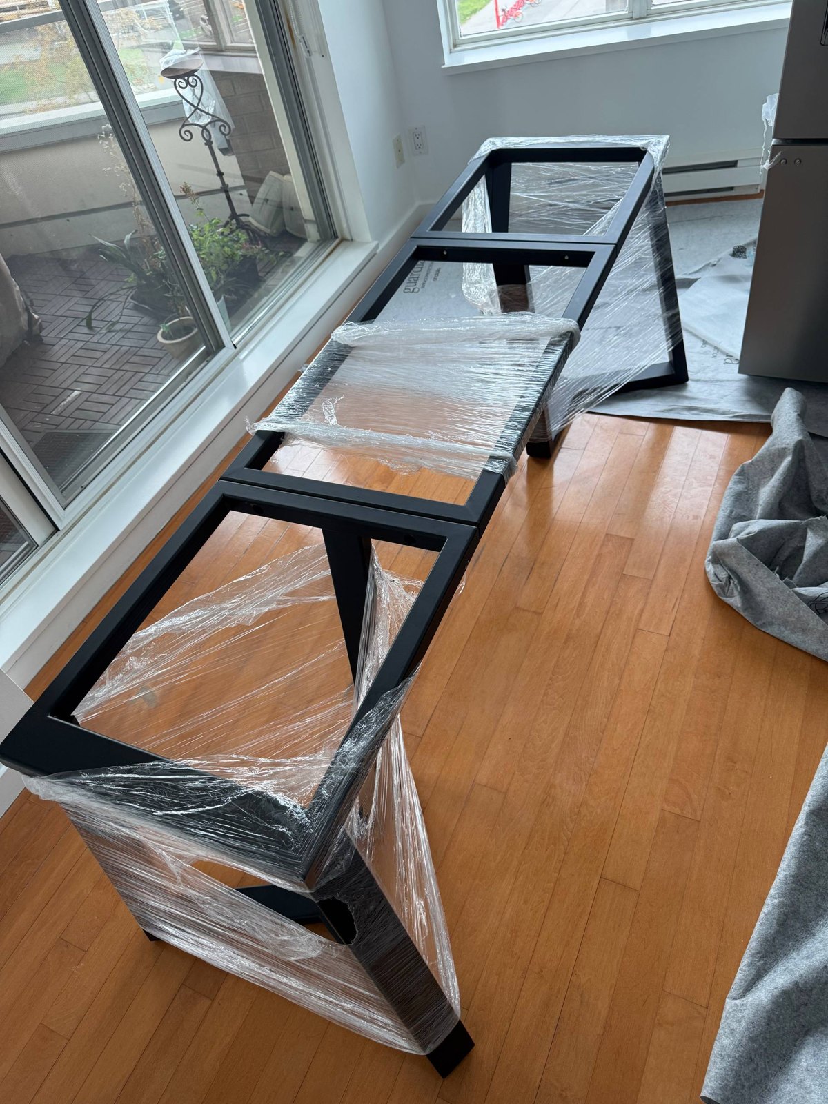 Full-length welded steel table frame wrapped and protected before install