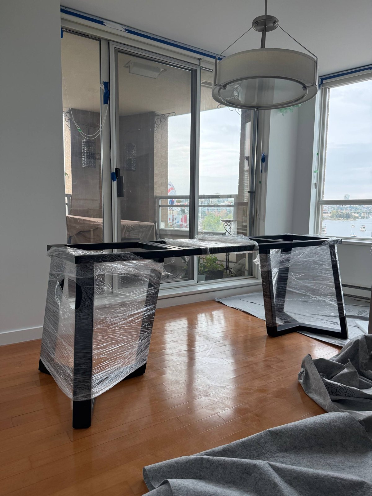 Wrapped steel table base sections on site during installation in a Vancouver apartment
